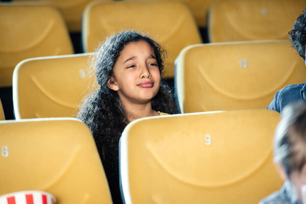 cute sad african american child crying while watching movie in cinema