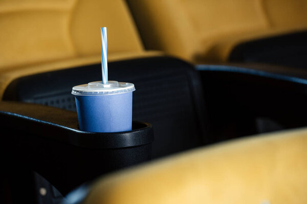 selective focus of cinema seat with blue disposable cup in cup holder 