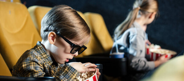 panoramic shot of cute boy in 3d glasses eating popcorn in cinema