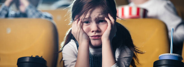 panoramic shot of upset child watching movie in cinema