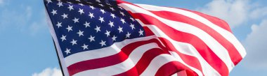 panoramic shot of american flag with stars and stripes against blue sky clipart