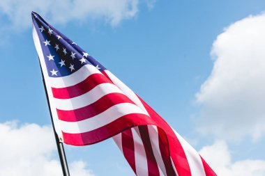 bulutlar ile mavi gökyüzüne karşı Amerikan bayrağı üzerinde yıldız ve çizgiler düşük açı görünümü