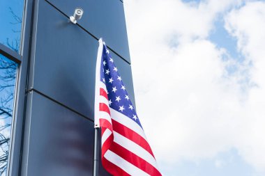 bulutlar ile gökyüzüne karşı bina yakınında yıldız ve çizgiler ile Amerika 'nın Ulusal bayrağı düşük açı görünümü 