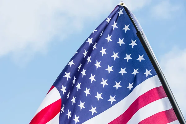 american flag with stars and stripes against sky with clouds 