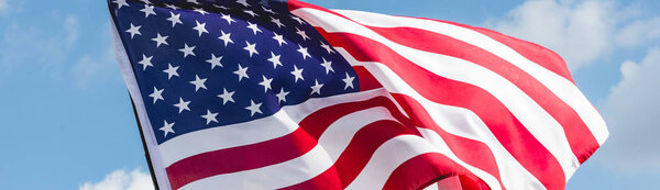 панорамный снимок американского флага со звездами и полосами на фоне голубого неба
