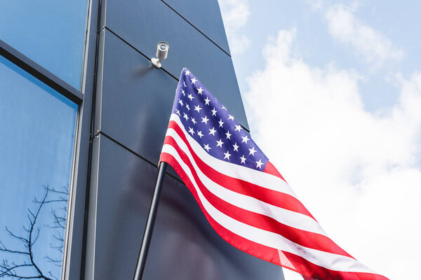 low angle view of national flag of america with stars and stripes near building against blue sky with clouds 