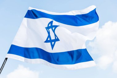 low angle view of national israel flag with star of david against blue sky clipart