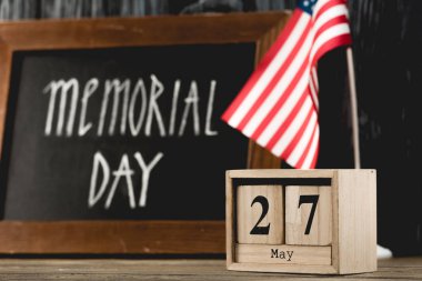wooden cubes with date near chalkboard with memorial day lettering and american flag  clipart