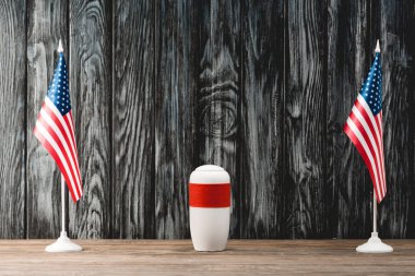funeral urn with ashes near american flags clipart