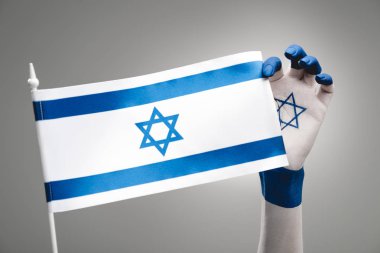 cropped view of female hand with star of david holding flag on grey clipart