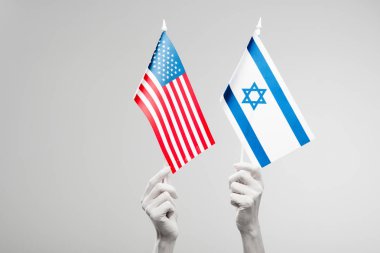 Beyaz tutan Amerikan ve İsrail bayrakları gri üzerinde izole kadın ellerin kırpılmış görünümü 