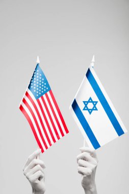 Beyaz tutma İsrail ve gri üzerinde izole Amerikan bayrakları boyalı kadın elleri kırpılmış görünümü 