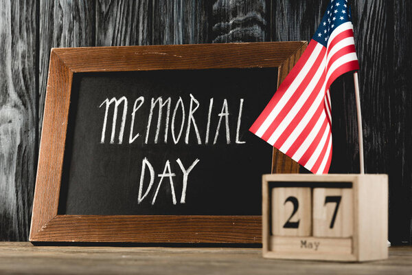 chalkboard with memorial day lettering  near wooden cubes with date and american flag 