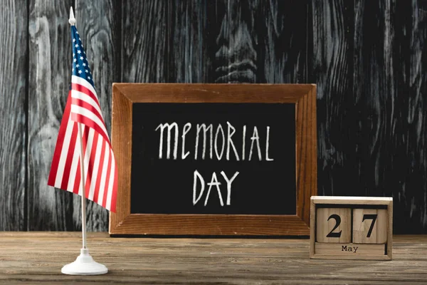 chalkboard with memorial day lettering near cubes with date and flag of america