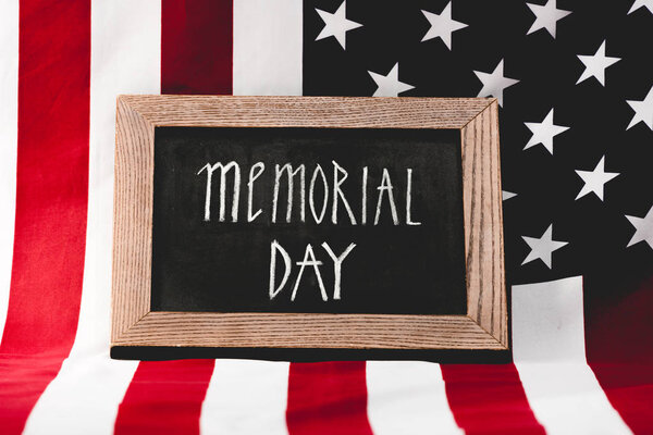 chalkboard with memorial day lettering near flag of america with stars and stripes