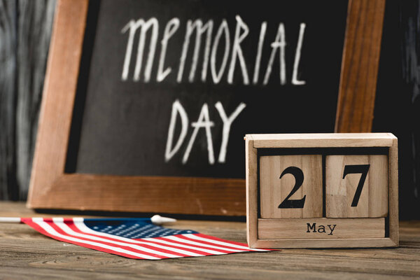 wooden cubes with date near flag of america with stars and stripes and memorial day lettering on chalkboard 