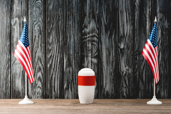 funeral urn with ashes near american flags