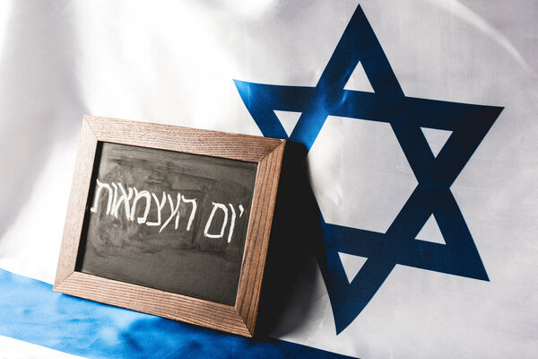 chalkboard with hebrew lettering near national flag of israel 