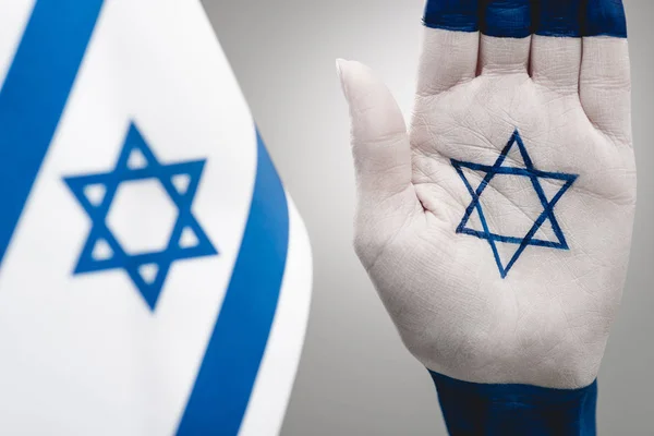 selective focus of female hand with star of david near flag on grey