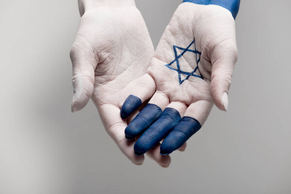 Обрезанный вид рук с голубой звездой давида на сером
