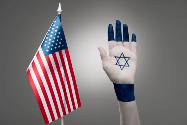 cropped view of female hand with star of david near american flag on grey