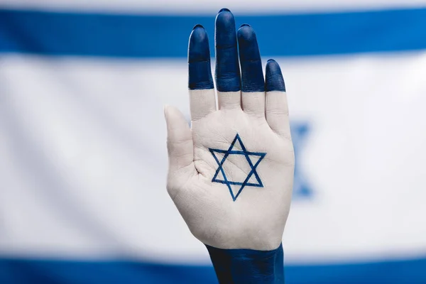 cropped view of female hand with star of david near flag