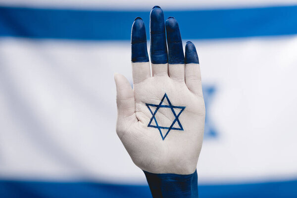 cropped view of female hand with star of david near flag 