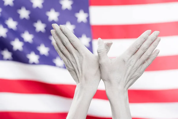 アメリカの国旗の近くの鳥の形のサインを示す白で描かれた女性の手のクロップドビュー — ストック写真