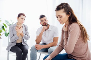 women and man sitting on chairs during group therapy session clipart