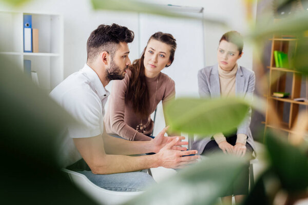 selective focus of women and man sitting during group therapy session