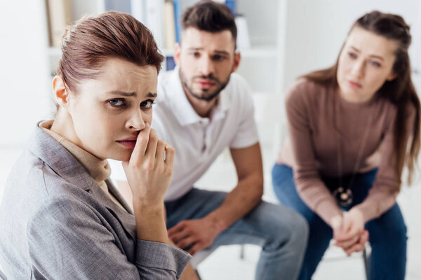 depressed woman looking at camera during group therapy session