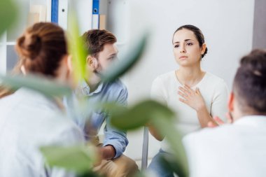 selective focus of woman gesturing during group therapy meeting clipart