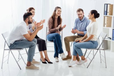 group of people sitting on chairs and applauding during therapy session clipart