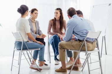 people sitting in circle during support group therapy meeting clipart