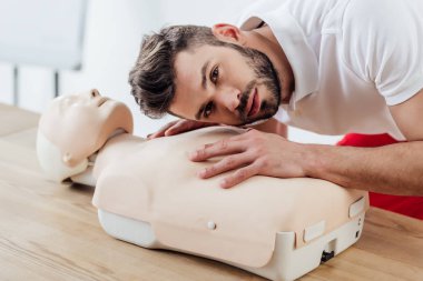 ilk yardım eğitimi sırasında kukla cpr tekniği pratik yaparken kameraya bakan adam