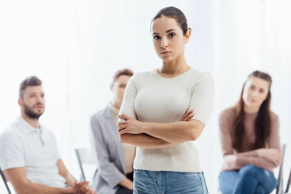 Mujer Con Los Brazos Cruzados Mirando Cámara Mientras Gente Sentada — Foto de Stock