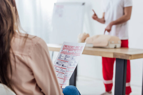 back view of woman holding first aid instruction during cpr training class