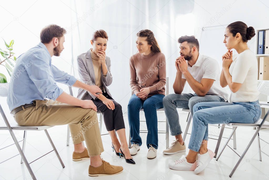 people sitting on chairs and having group therapy meeting