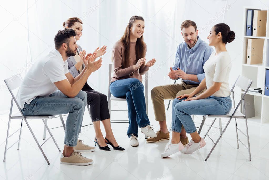 group of people sitting on chairs and applauding during therapy session