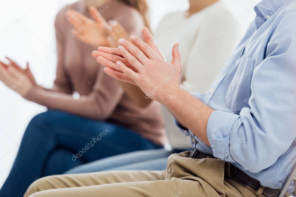 cropped view of people sitting and applauding during group therapy session