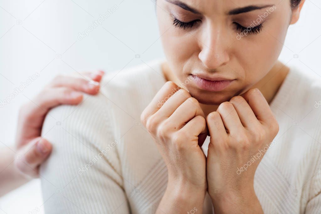 selective focus of depressed woman with clenched fists during therapy meeting