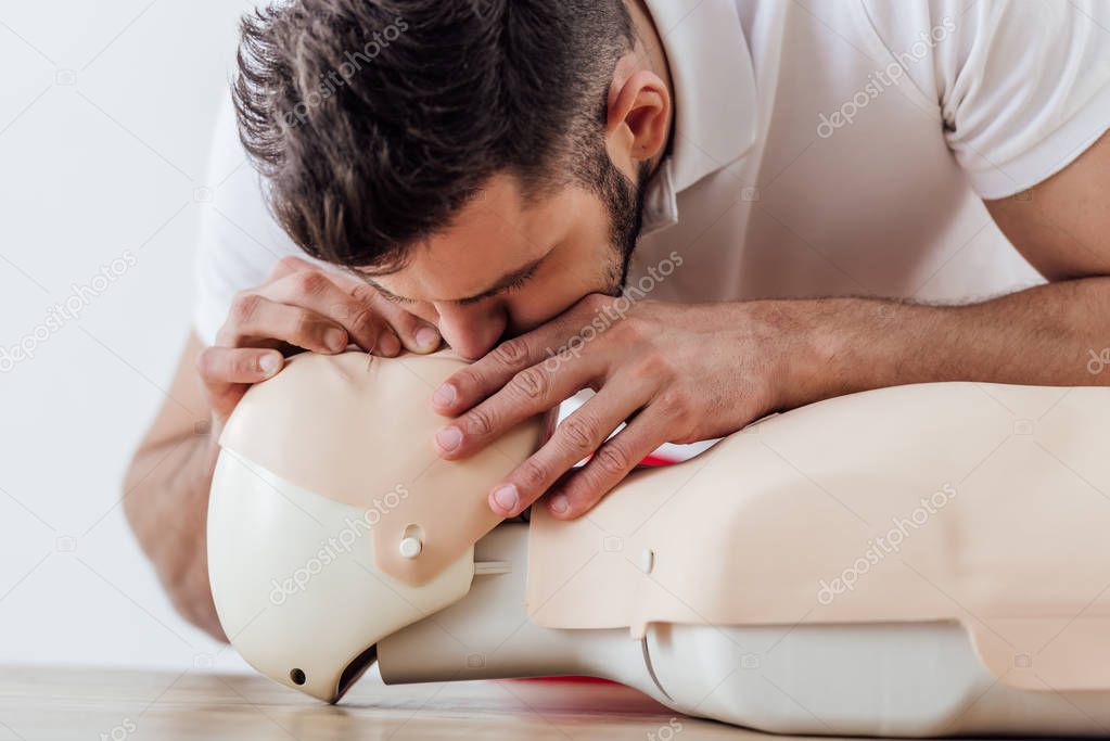 man using mouth to mouth technique on dummy during cpr training 