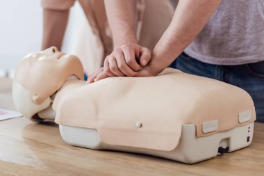 Adamın göğüs sıkıştırma kukla üzerinde cpr eğitim sınıf sırasında gerçekleştirerek kısmi görünümü