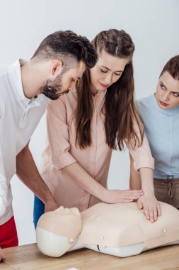 beautiful woman performing chest compression on dummy during cpr training class clipart