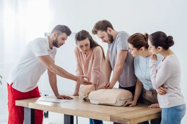 Grupa Ludzi Przystojnym Instruktorem Wykonywania Cpr Manekina Trakcie Szkolenia Pierwszej — Zdjęcie stockowe