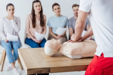 Arkadan bir grup insan ile ilk yardım eğitimi sırasında kukla üzerinde cpr performans eğitmen görünüşü