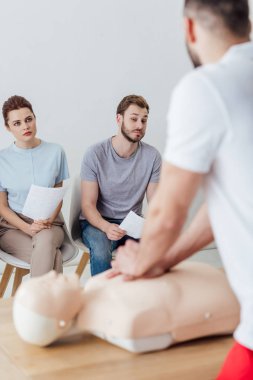 arkadan görünüşü sırasında cpr eğitim sınıfı ile bir grup insan kukla üzerinde göğüs sıkıştırma gerçekleştirerek eğitmen