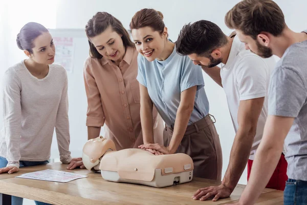 Hermosa Mujer Sonriente Mirando Cámara Mientras Realiza Cpr Maniquí Durante —  Fotos de Stock