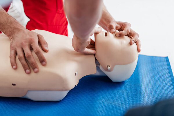 cropped view of men practicing cpr technique on dummy during first aid training