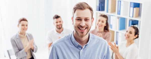 панорамный снимок улыбающегося мужчины, смотрящего в камеру во время сеанса групповой терапии
